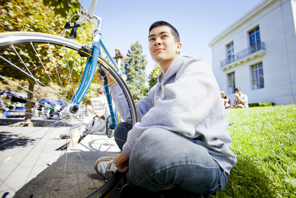Student sits next to bike at UC Berkeley