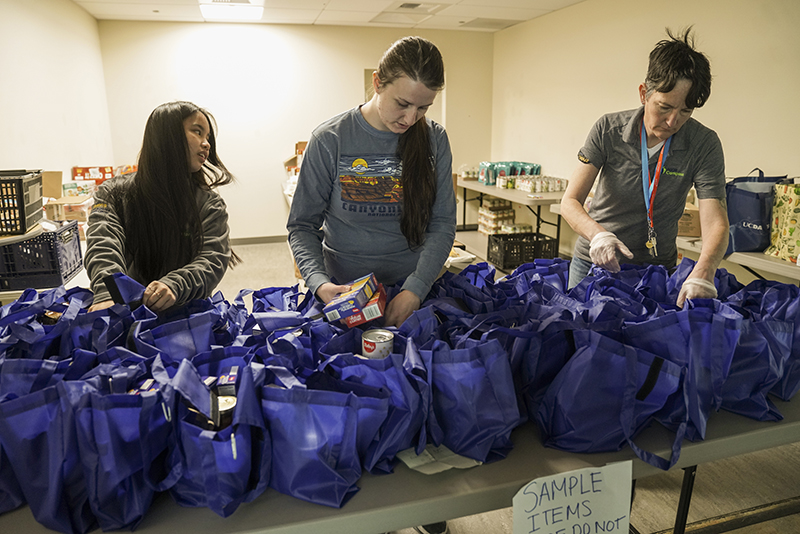 Three students filling bags of donated food