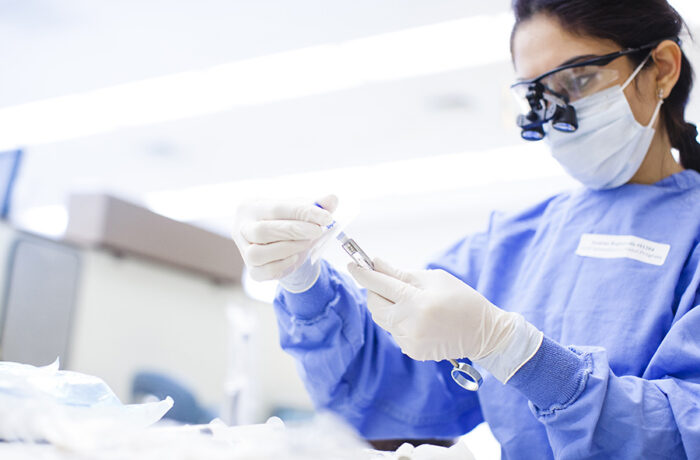 Woman in PPE examines syringe