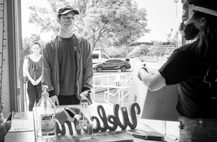 Black and white photo of young man in a mask receiving a box