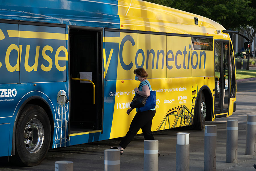Woman in mask boards a Causeway Connection bus at UC Davis Health