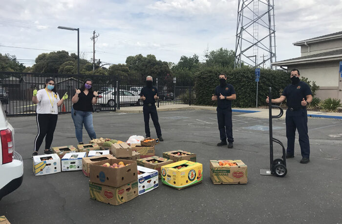 Students in masks stand in front of donated food in a parking lot at UC Merced
