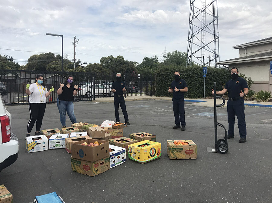 Students in masks stand in front of donated food in a parking lot at UC Merced