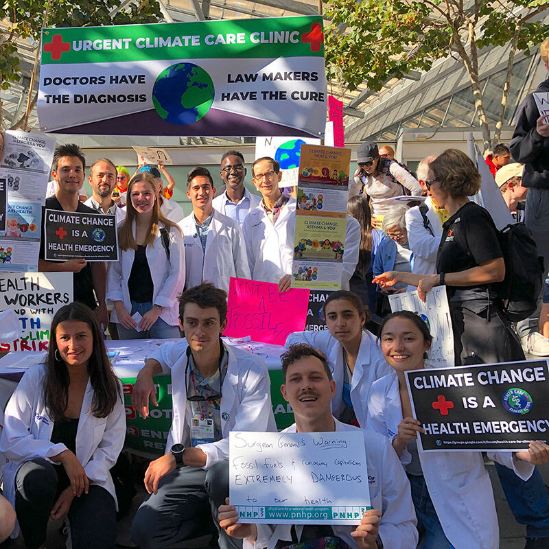 Medical Students in white coats holding signs at the UCCC Climate March