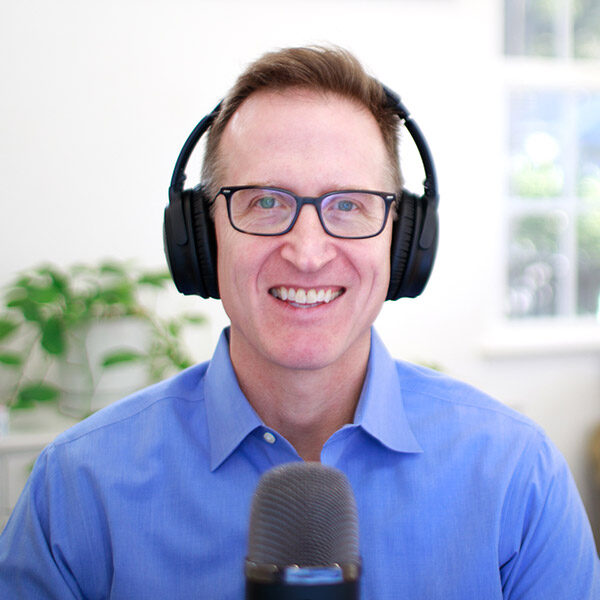David Phillips, AVP of Energy & Sustainability, headshot with earphones in front of a microphone