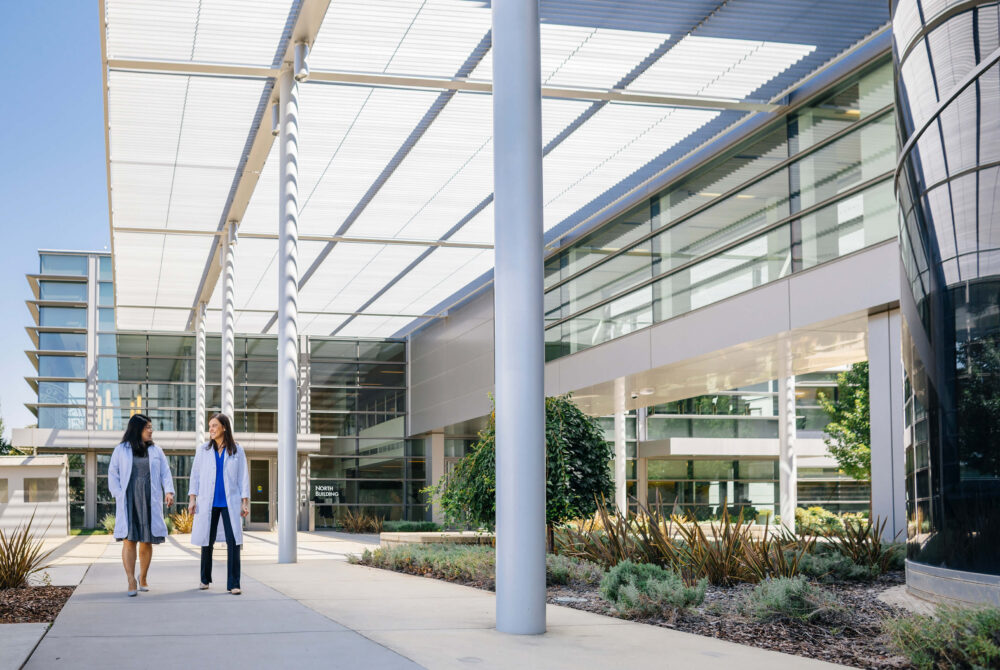View of UC Davis Medical Building with two females walking in lab coats
