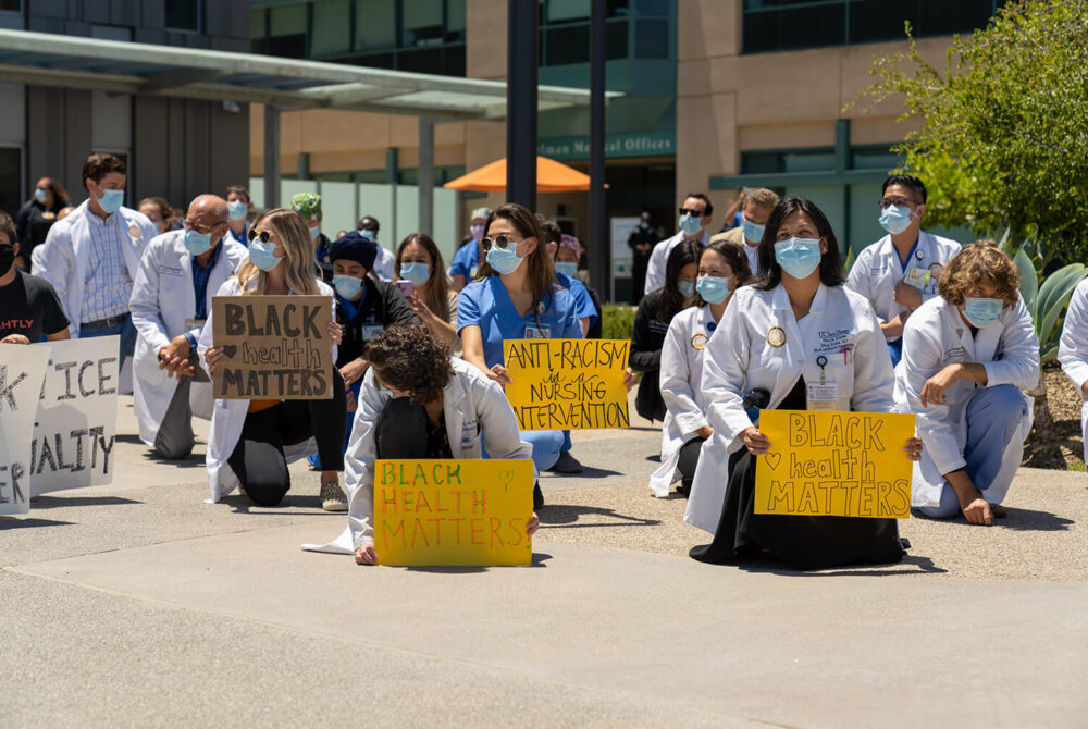 A group of medical professionals kneeling and holding "black health matters" signs
