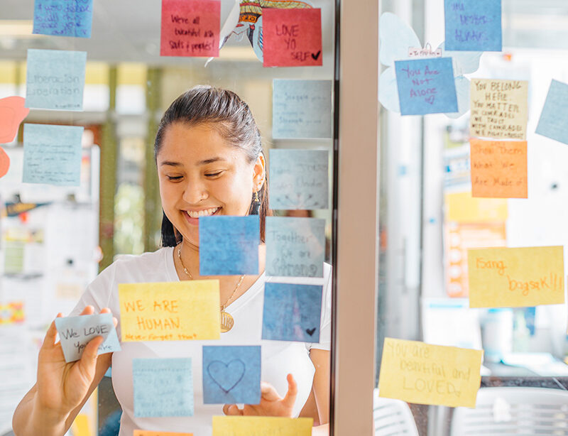 Student posting positive messages on sticky notes to a glass wall