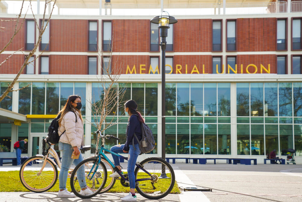 Two students on bikes outside of the Memorial Union at UC Davis