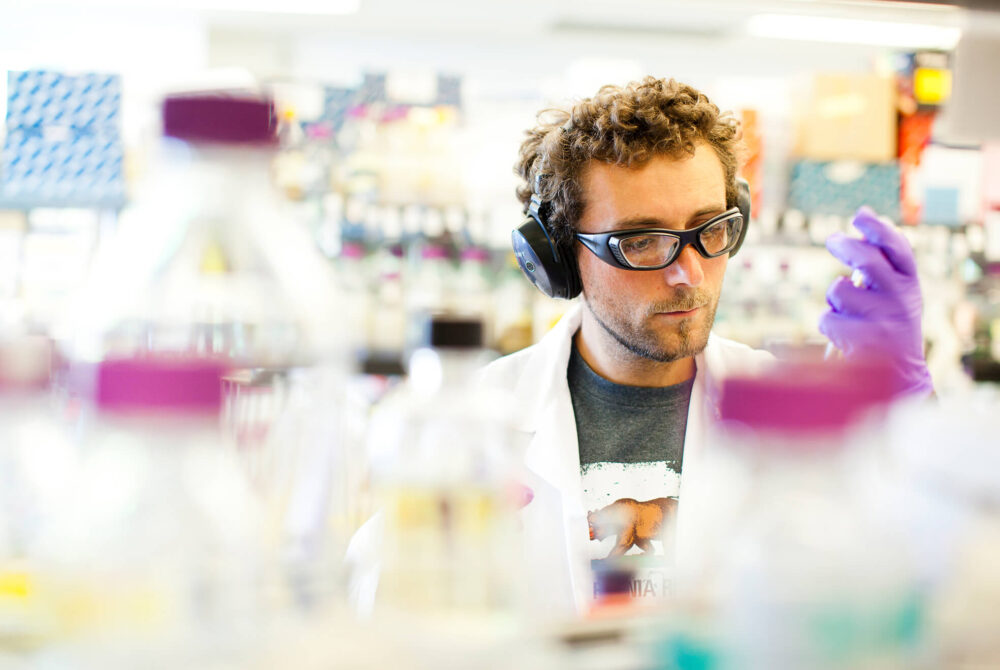 Male graduate student in lab examining substance in test tube
