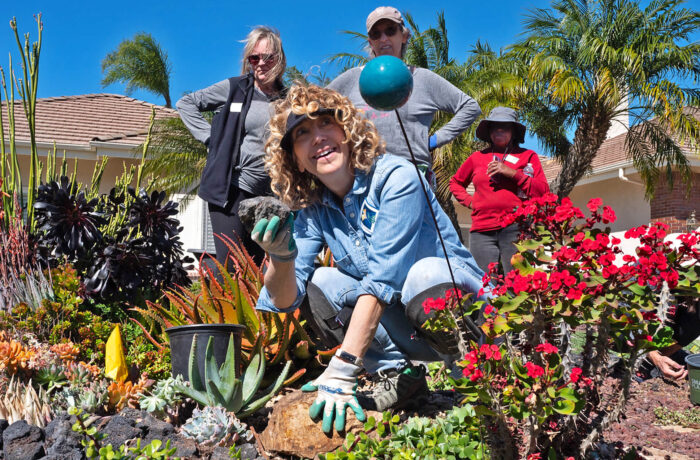 Master Gardener teacher in flower bed discussing gardening to a group