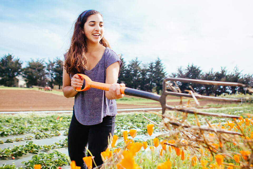 Female student in garden with pitch fork