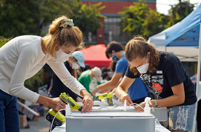 Two people assembling air purifier with electric screwdriver