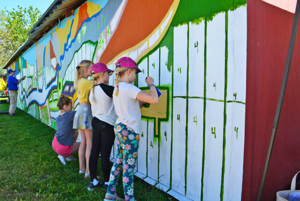 Community members helping paint the winning mural design on barn wall