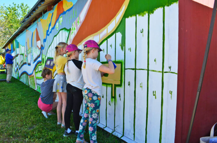 Community members helping paint the winning mural design on barn wall