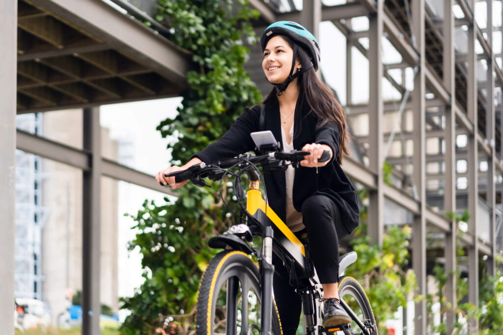 Young woman on bike, while wearing helmet, riding through city