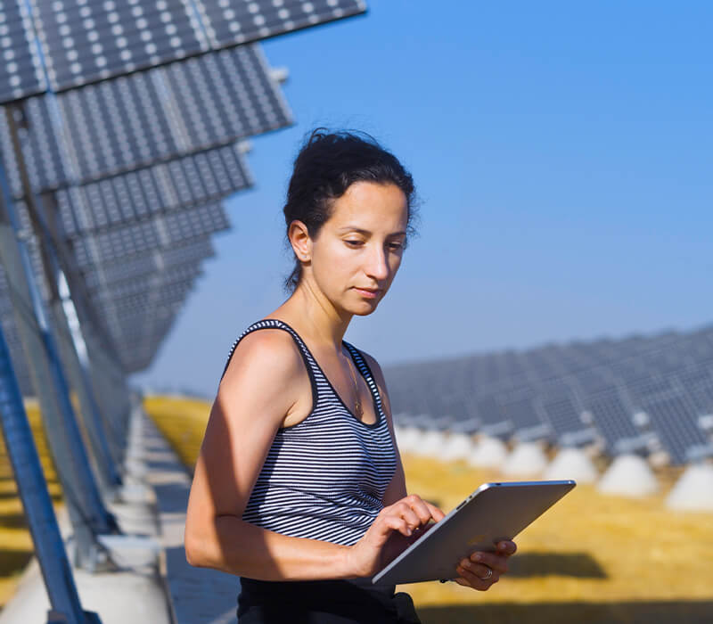 Women on iPad surrounded by solar panels