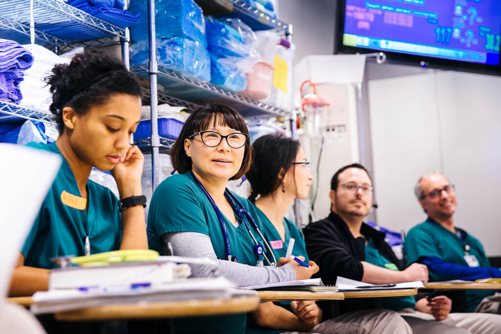 UC San Francisco Health health care workers sit at desks and take notes.