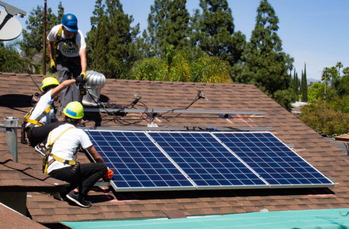 People installing a solar panel on a roof