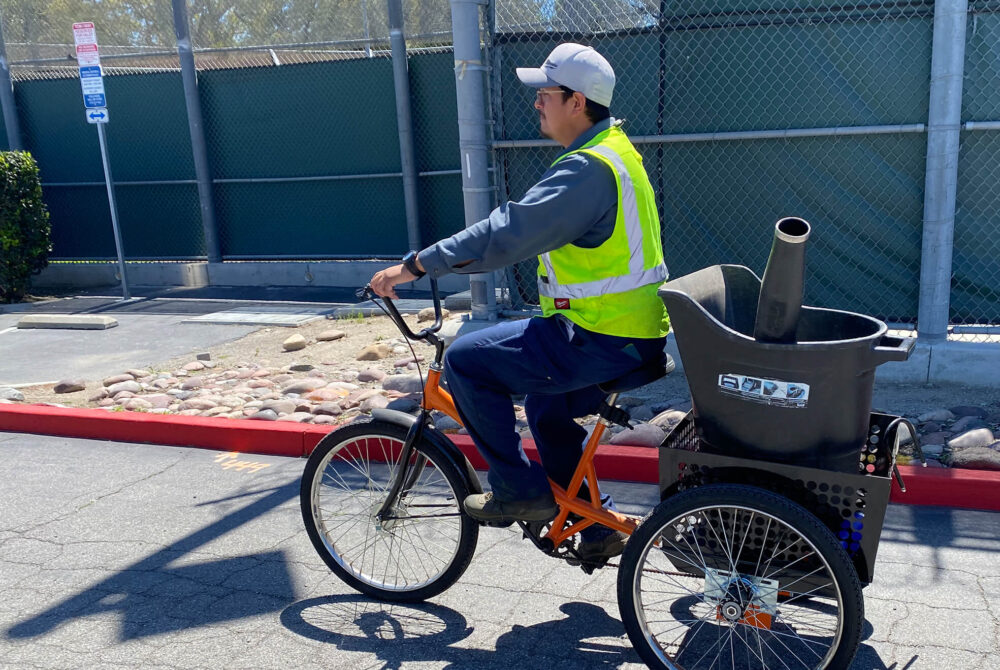 Grounds staff on bike with electric landscaping